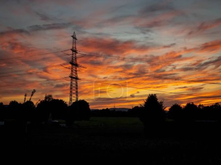 Foto de Una silueta de árboles y una torre de transmisión durante una puesta de sol - Imagen libre de derechos