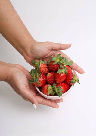Photo for A vertical shot of a female holding a white bowl with strawberries inside - Royalty Free Image