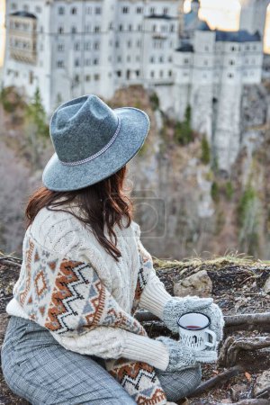 Photo for A female tourist with a gray hat admiring Neuschwanstein castle in Germany from a hill - Royalty Free Image