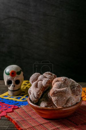 Foto de El tiro vertical del cráneo pequeño y el pan de los muertos sobre la tela roja sobre la mesa - Imagen libre de derechos