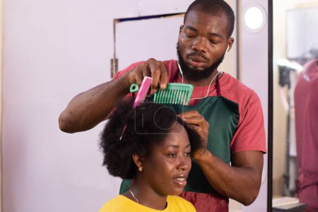 Téléchargez les photos : Homme africain faisant les cheveux d'une dame - en image libre de droit