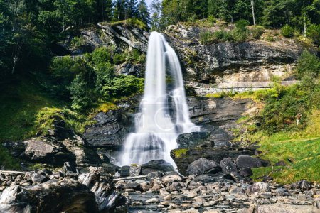 Téléchargez les photos : Une vue panoramique d'une cascade descendant les rochers dans une zone rurale sous la lumière du soleil - en image libre de droit