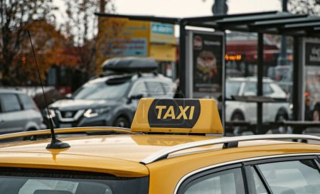 Foto de Un primer plano de un cartel de taxi en la parte superior de un coche amarillo que monta en una calle concurrida - Imagen libre de derechos