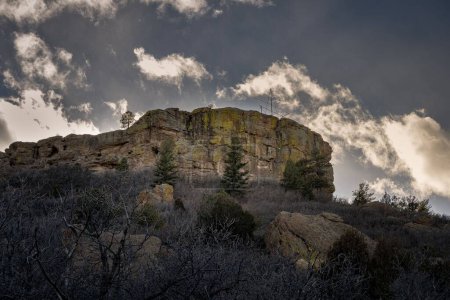 Photo for A low angle of a rock formation on a hilltop surrounded by firs and stones under the moody sky in Castle Rock, Colorado - Royalty Free Image