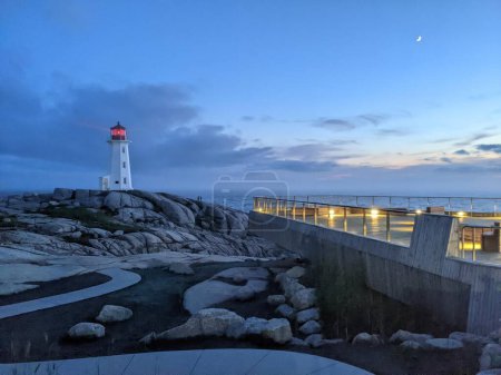 Téléchargez les photos : Un phare sur le rivage rocheux avec une mer en arrière-plan pendant le coucher du soleil - en image libre de droit