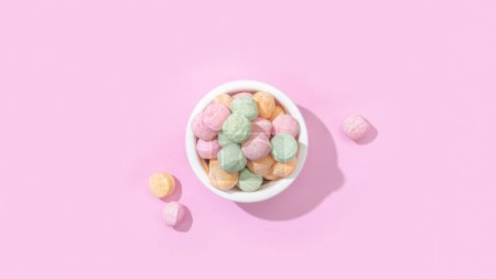 Foto de Una vista superior de un tazón de caramelos de gelatina con diferentes sabores aislados sobre un fondo rosa pastel - Imagen libre de derechos