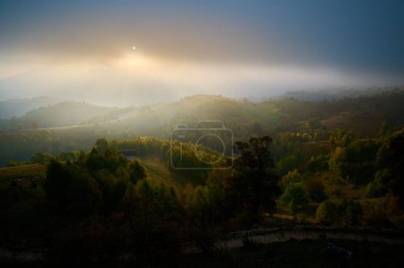 Téléchargez les photos : Une vue aérienne des montagnes couvertes de forêts au coucher du soleil par une journée brumeuse - en image libre de droit
