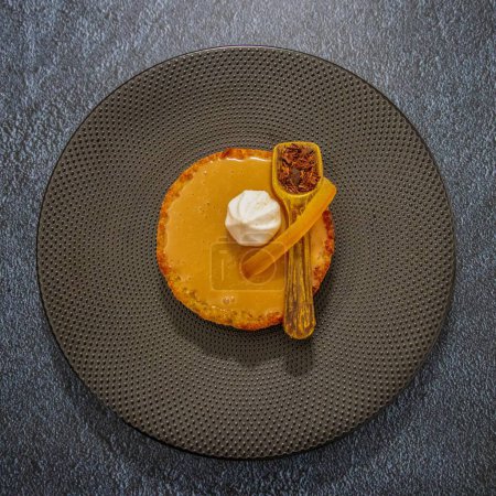 Photo for A top view of delicious round Pumpkin pie with spoon on large brown plate - Royalty Free Image