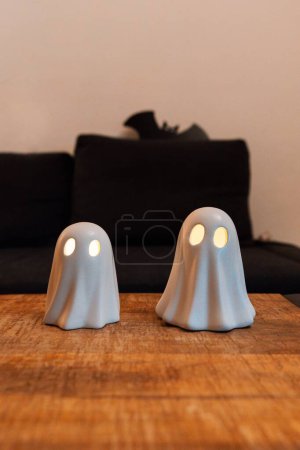 Foto de Un disparo vertical de dos figuras fantasma de Halloween con ojos iluminados y un juguete de murciélago en el fondo - Imagen libre de derechos