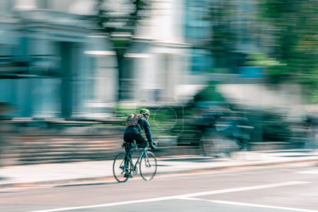 Photo for A panning shot of a male in a backpack cycling on the Oxford Road in Manchester, UK - Royalty Free Image