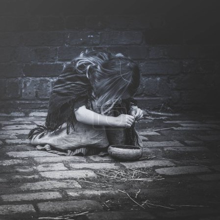 Photo for A Ragged young girl playing on cobblestones in the street - Royalty Free Image