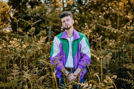 Téléchargez les photos : Un homme caucasien debout dans une forêt et regardant la caméra sur fond flou - en image libre de droit