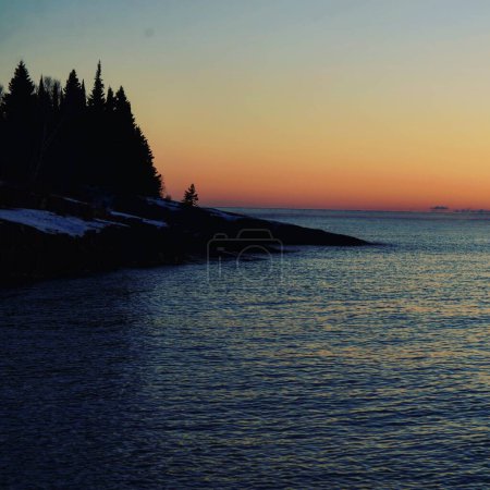 Téléchargez les photos : Une vue panoramique d'un rivage avec des arbres et un beau coucher de soleil en arrière-plan - en image libre de droit