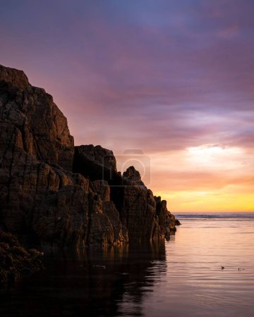 Photo for A vertical view of Woolacombe sea and cliffs under the purple and yellow sky of summer 2022 - Royalty Free Image