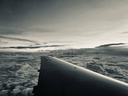 Photo for A dark shot of the wing of a plane in the clouds during its flight - Royalty Free Image