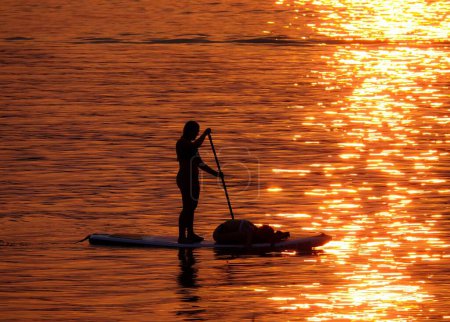 Foto de Una silueta de un pescador en un Paddleboard en el brillante atardecer del lago Denver en Colorado - Imagen libre de derechos