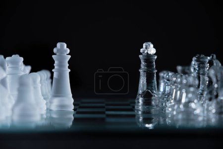 Téléchargez les photos : Un gros plan de pièces d'échecs en cristal sur un panneau de verre sur fond noir - en image libre de droit