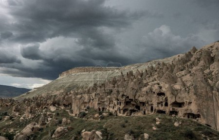 Photo for An aerial view of carved houses in rock in Pigeon Valley in Cappadocia, Turkey, with a stormy sky in the background - Royalty Free Image
