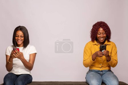 Photo for Happy africans girls checking their phones - Royalty Free Image
