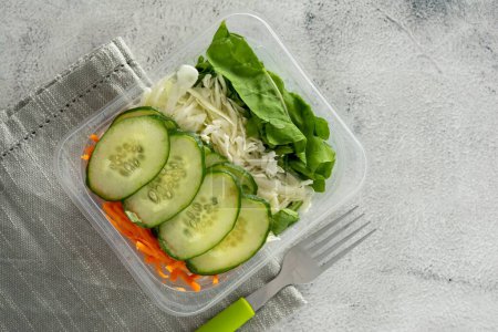 Photo for A top view of the vegetarian salad with cucumber, carrot and cabbage with a fork on a table - Royalty Free Image