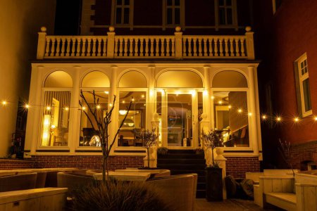 Foto de Un plano nocturno de un pequeño restaurante estético decorado con luces y muebles elegantes - Imagen libre de derechos