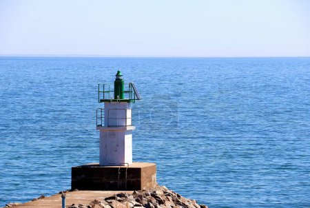 Téléchargez les photos : Une belle vue d'un phare sur un rivage d'une mer bleue calme au lever du soleil - en image libre de droit