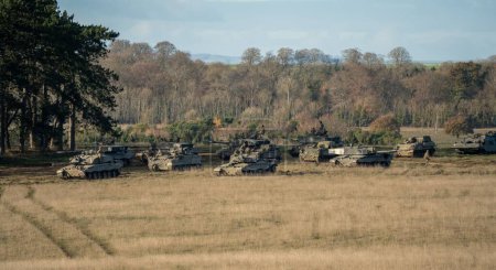 Foto de Un escuadrón de tanques de batalla del ejército que se mueven en un campo - Imagen libre de derechos
