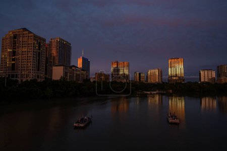 Foto de Un disparo de dron de barcos en el lago de la ciudad con arquitecturas de Austin en el fondo por la noche - Imagen libre de derechos