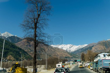 Foto de Escénica vista de invierno desde el camino de asfalto en las montañas cubiertas de nieve y árboles en el lado de la carretera sobre un fondo de cielo azul y nubes - Imagen libre de derechos