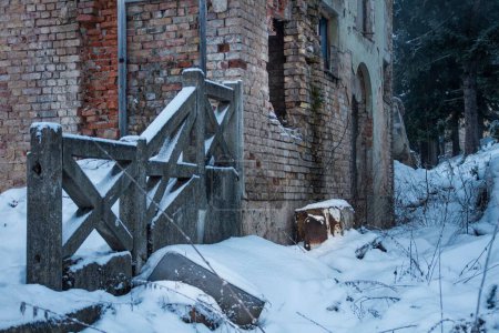 Foto de Una vieja casa de ladrillo abandonada en ruinas después de la guerra cubierta de nieve - Imagen libre de derechos