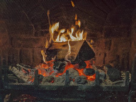 Foto de Una chimenea ardiente detrás de rejilla patrón de metal en casa - Imagen libre de derechos