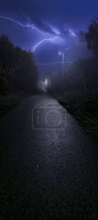 Foto de Una hermosa toma de un trueno y un rayo sobre un camino vacío - Imagen libre de derechos