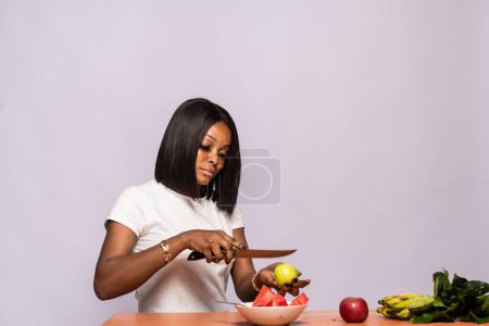 Téléchargez les photos : Belle dame africaine découper quelques fruits - en image libre de droit
