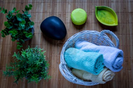 Téléchargez les photos : Une vue de dessus de serviettes colorées dans un panier, savons et plantes sur un sol en bois - en image libre de droit