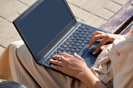 Téléchargez les photos : Gros plan d'une jeune femme travaillant sur son ordinateur portable avec un écran vide dans un parc - en image libre de droit