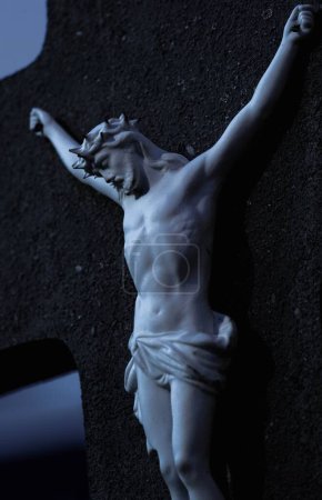 Foto de Un disparo vertical de una estatua de Jesucristo crucificado en una cruz negra - Imagen libre de derechos