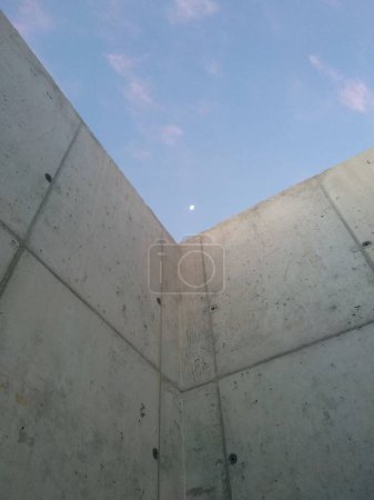 Téléchargez les photos : Plan vertical d'un mur avec la lune visible dans le ciel pendant l'après-midi - en image libre de droit