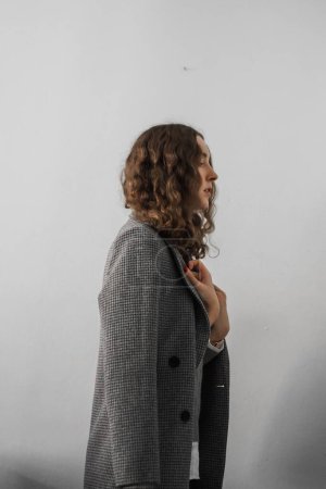 Téléchargez les photos : Une femme caucasienne portant un manteau gris posant en fond blanc - en image libre de droit