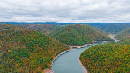 Photo for An aerial of a scenic lake surrounded by a dense forest with autumn foliage in fall colors - Royalty Free Image