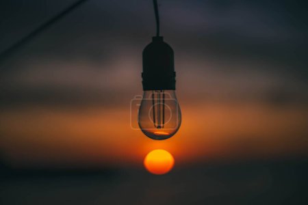 Téléchargez les photos : Une mise au point sélective d'une ampoule au-dessus du soleil lors d'un beau coucher de soleil - en image libre de droit