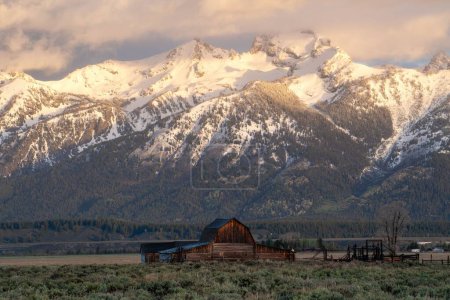Photo for A small hut with the snowy peaks of the Grand Tetons mountains in the background during the daytime - Royalty Free Image