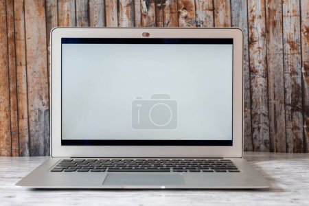 Foto de Un primer plano de un ordenador portátil con pantalla en blanco y fondo de pared de madera, concepto de tecnología en línea - Imagen libre de derechos