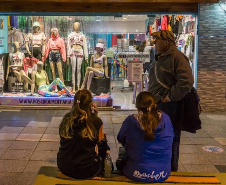 Téléchargez les photos : Une famille s'assoit devant un magasin plein de mannequins, la nuit - en image libre de droit
