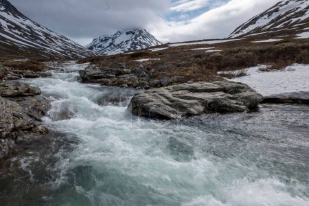 Téléchargez les photos : Un beau plan de rivière coulant sur la vallée de Visladen près des montagnes à Piterstulen, Jotunheimen, Norvège - en image libre de droit