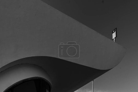 Photo for A black and white view of a console lamp behind a building during daytime - Royalty Free Image