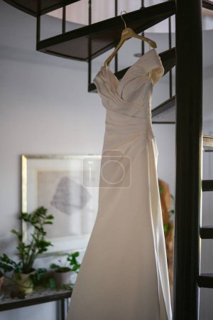 Foto de Un tiro vertical de ángulo bajo de un vestido de novia blanco colgado de una escalera de caracol - Imagen libre de derechos