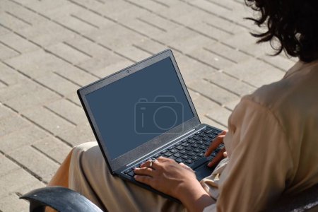Foto de Un primer plano de una joven mujer trabajando en su portátil con una pantalla en blanco durante el día - Imagen libre de derechos