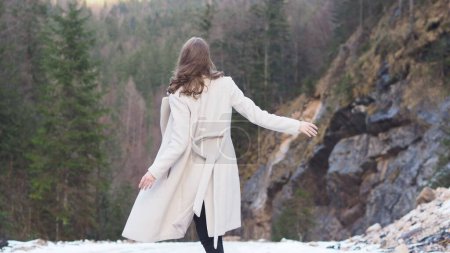 Téléchargez les photos : Une jeune et belle femme caucasienne avec un manteau blanc posant dans la forêt - en image libre de droit