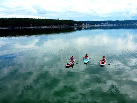 Photo for Three people paddleboarding on the St Lawrence river in the summer - Royalty Free Image