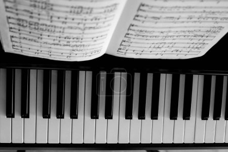 Téléchargez les photos : Gros plan d'un piano noir avec des notes de musique - en image libre de droit